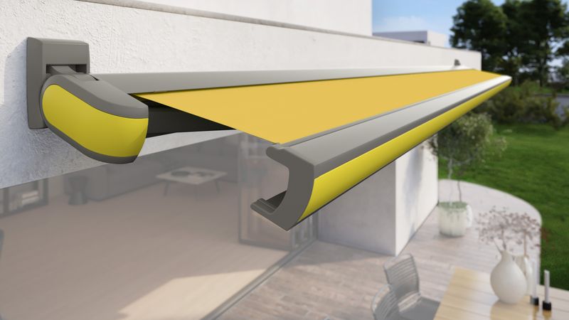 cassette awning MX-3 with yellow fabric cover, gray frame and yellow cover profile fixed to a house wall