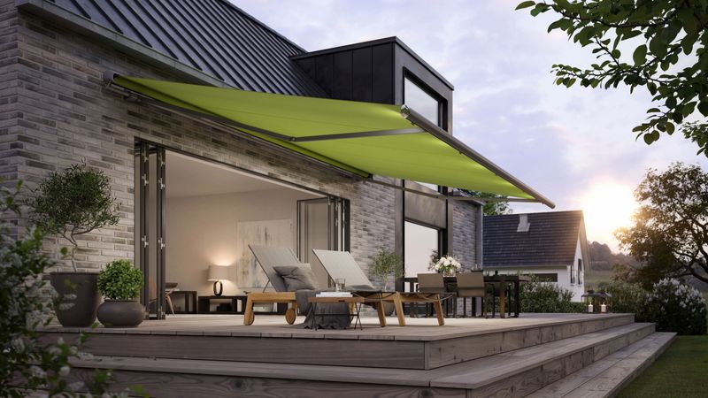Semi-cassette awning markilux 1600 extended, with green cloth on gray brick wall