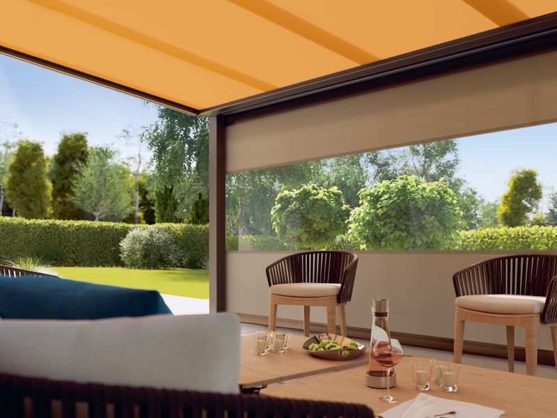 Terrace roof with seating area protected from the wind by a vertical blind type markilux 776/876 with panoramic window.