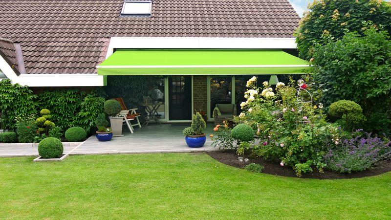 White awning markilux 1710 with bright green fabric cover and valance over a terrace in a building alcove.